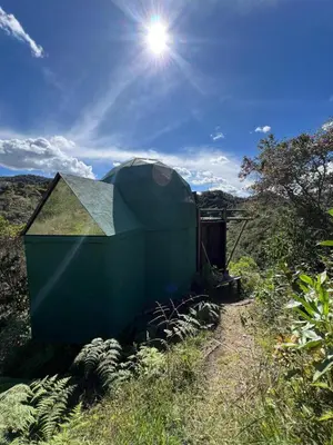 a green building sitting in the middle of a field at Ikuna Luxury Glamping 1h from Medellin with Private Jacuzzi in San Vicente