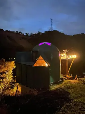 a tent sitting in a field at night at Ikuna Luxury Glamping 1h from Medellin with Private Jacuzzi in San Vicente