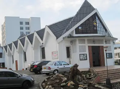a large white building with cars parked in a parking lot at El Mejor Aparta Estudio De La Ciudad in Manizales