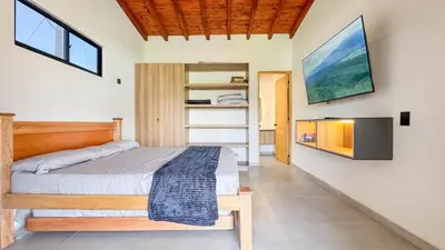 a bedroom with a bed and a tv on a wall at Finca Monteverde House in San Isidro
