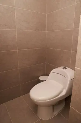 a bathroom with a toilet and a tiled wall at VPV Suites & Casino in Medellín