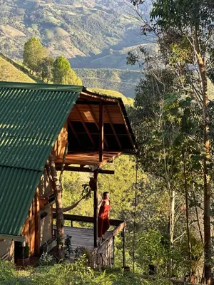 a woman standing on the porch of a house at Alto Bonito Cabin Salamina in Salamina