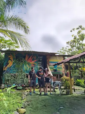 three people and a dog standing in front of a house at Rocas del Rio Ecohotel in Mutatá