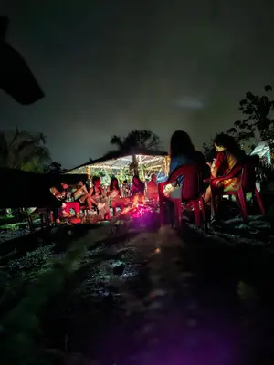 a group of people sitting around a fire at night at Rocas del Rio Ecohotel in Mutatá