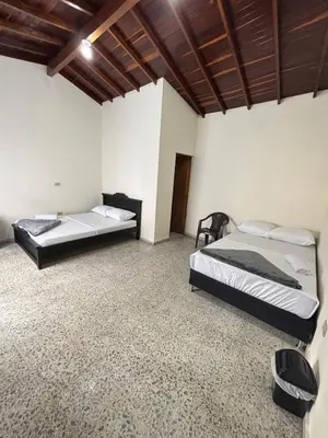 two beds in a room with white walls and wooden ceilings at Hospedaje Doña Blanca in Concepción