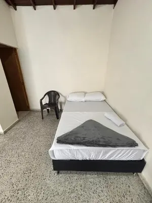 a bedroom with a bed and a chair at Hospedaje Doña Blanca in Concepción