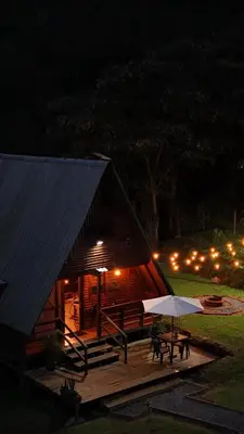 a cabin with a table and an umbrella at night at Maderalia in El Salvador