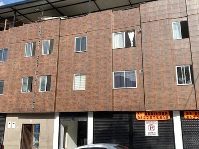 a brick building with windows and a car parked in front at Hotel el CONDADO in Itagüí