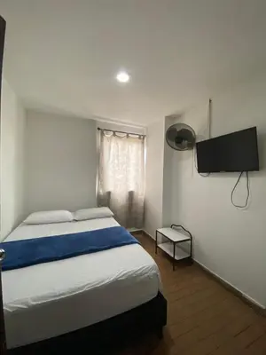 a bedroom with a bed and a flat screen tv at Hotel el CONDADO in Itagüí