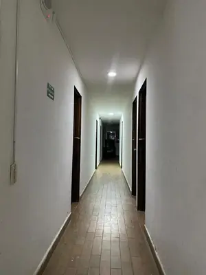 an empty hallway with white walls and a tile floor at Hotel el CONDADO in Itagüí