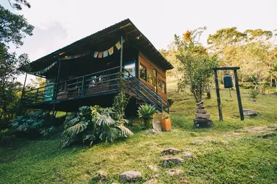 a house with a balcony on a grass field at El Santuario Retreat in Guatapé