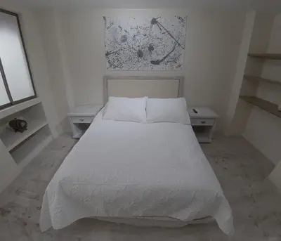 a white bed in a white bedroom with two tables at Apartamento Manizales excelente ubicación in Manizales