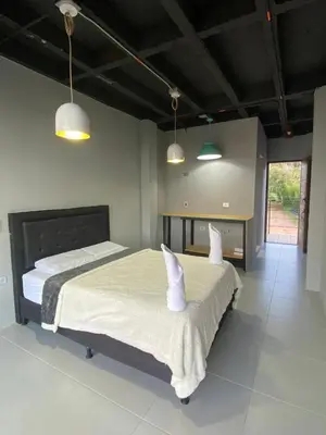 a bedroom with two beds with white sheets and two lights at Nakawe Guatape in Guatapé