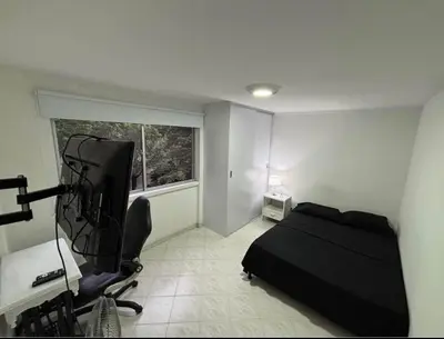 a bedroom with a bed and a desk and a television at Happy house in Medellín