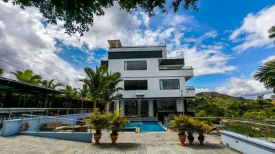 a white building with a swimming pool and palm trees at The Palms Hotel in Estación El Salto