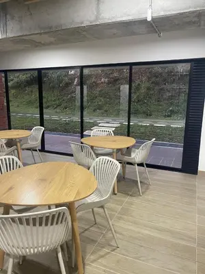 a cafeteria with tables and white chairs and windows at Hermoso apartamento tipo loft en El Retiro Oriente Ant in El Retiro