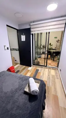 a bedroom with a bed and a balcony with a table at Bravas Medallo in Medellín