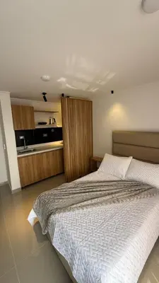 a bedroom with a large bed and a kitchen at Lunaria House - Laureles in Medellín
