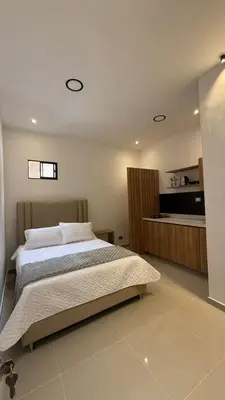 a bedroom with a large bed and a kitchen at Lunaria House - Laureles in Medellín