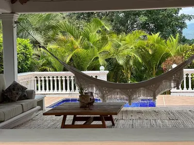 a hammock on a porch with a couch and a table at Finca La Verbena in San Jerónimo