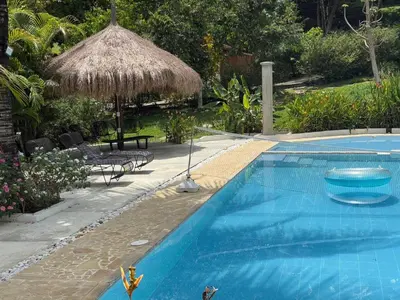 a swimming pool with a straw umbrella and toy people in the water at Finca La Verbena in San Jerónimo