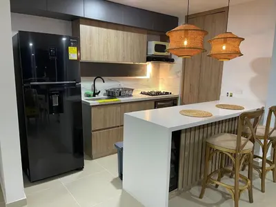a kitchen with a black refrigerator and a counter at HERMOSO APARTAMENTO CITADELA DI SOLE EN SANTAFE DE ANTIOQUIa in Santa Fe de Antioquia