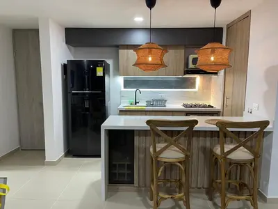 a kitchen with a black refrigerator and two bar stools at HERMOSO APARTAMENTO CITADELA DI SOLE EN SANTAFE DE ANTIOQUIa in Santa Fe de Antioquia