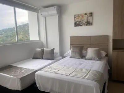two beds in a room with two windows at HERMOSO APARTAMENTO CITADELA DI SOLE EN SANTAFE DE ANTIOQUIa in Santa Fe de Antioquia