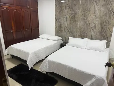 two beds with white sheets in a room at Lumière House in Medellín