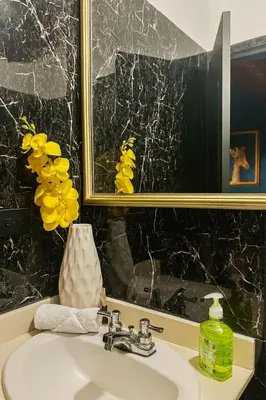 a bathroom sink with a mirror and a vase with yellow flowers at Casa amplia con estilo, poblado, disco y AC in Medellín