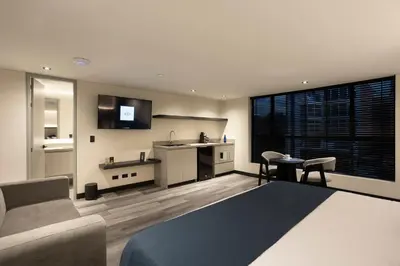a bedroom with a bed and a desk and a tv at Altus Hotel in Medellín