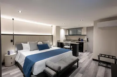 a bedroom with a large bed and a kitchen at Altus Hotel in Medellín