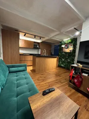 a living room with a green couch and a table at Industrial Chic Apartment Overlooking the City in Medellín