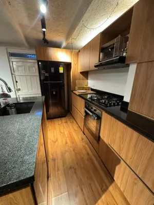 a kitchen with wooden cabinets and a black counter top at Industrial Chic Apartment Overlooking the City in Medellín