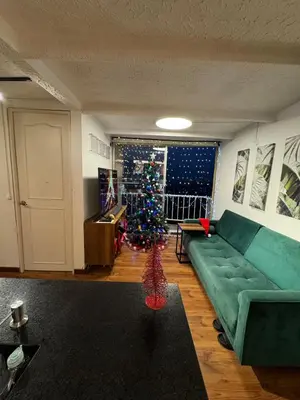 a living room with a green couch and a christmas tree at Industrial Chic Apartment Overlooking the City in Medellín