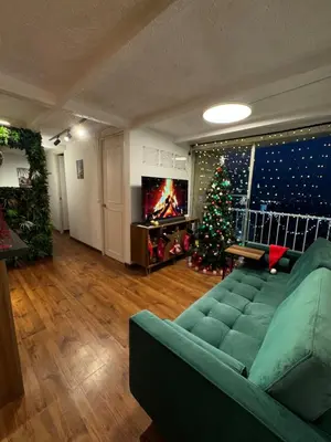 a living room with a green couch and a christmas tree at Industrial Chic Apartment Overlooking the City in Medellín