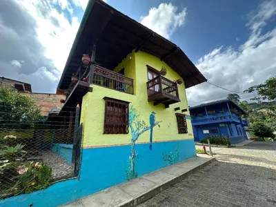 a yellow and blue house with a balcony at Melongos Jardín in Jardin