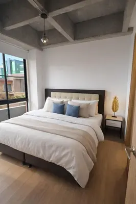 a bedroom with a large white bed with blue pillows at Envigado Luxury Stay - Apartment in City Plaza in Envigado