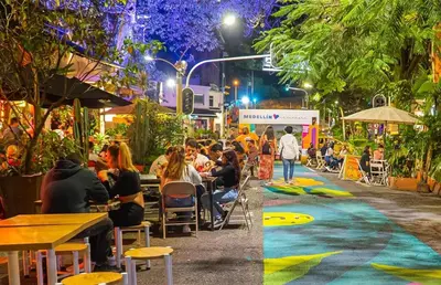 a group of people sitting at tables on a street at night at Envigado Luxury Stay - Apartment in City Plaza in Envigado