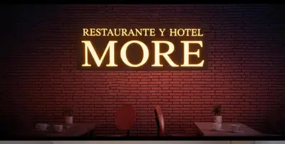 a neon sign on a brick wall in a restaurant at Hotel y Restaurante More in Supía