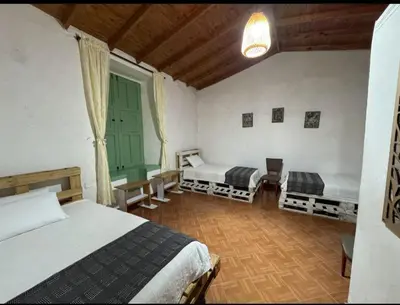a bedroom with two beds and a large window at Hostal Prana in Abejorral