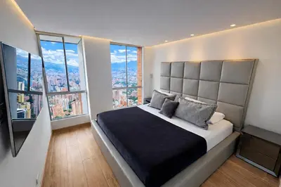 a bedroom with a large bed with large windows at El Poblado Two-Level Luxury Penthouse Amazing View in Medellín
