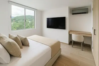 a bedroom with a bed and a desk and a television at El Poblado Amazing Penthouse with Breathtaking Views in Medellín
