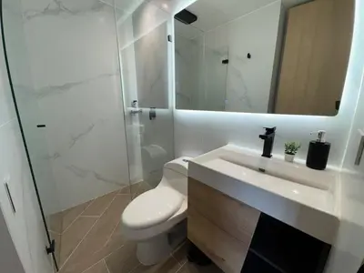 a bathroom with a toilet and a sink and a mirror at El Poblado Amazing Penthouse with Breathtaking Views in Medellín