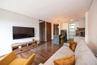 a living room with a couch and a tv and a kitchen at Apartamentos Casa Grande in Rionegro