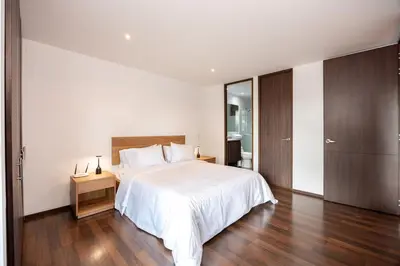 a bedroom with a white bed and a wooden floor at Apartamentos Casa Grande in Rionegro