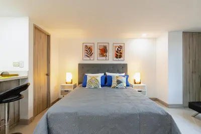 a bedroom with a large bed with blue pillows at Apartamentos La Frontera in Medellín