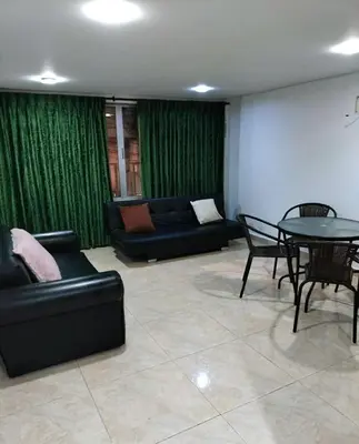 a living room with green curtains and a table and couch at Cómodo apartamento por días in Manizales