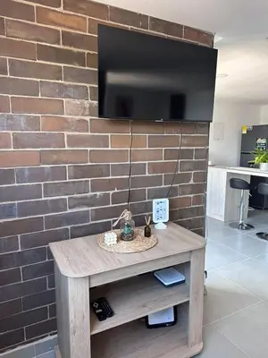 a brick wall with a tv and a wooden table at Sabaneta, aparta Loft, excelente Ubicacion, Wifi in Sabaneta