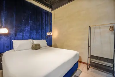 a white bed in a room with a blue wall at Lleras Vibex Party in Medellín